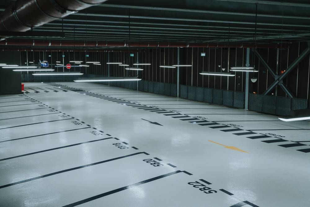 An empty parking garage illuminated by lights on the floor, featuring clear car park markings for guidance.