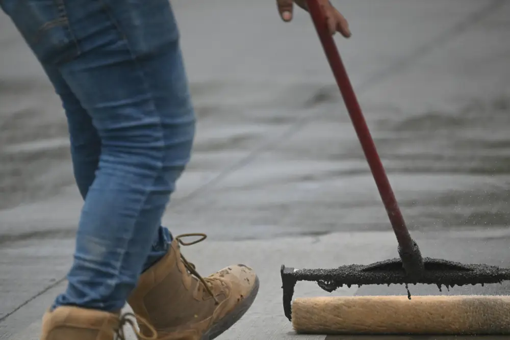 A person applying concrete with a roller, focusing on the sealing process for a smooth finish.