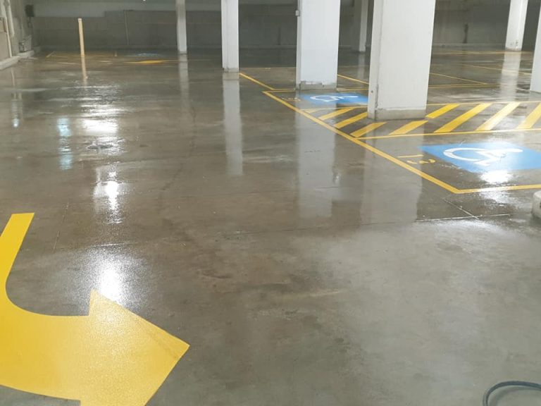 A parking garage featuring yellow arrows on a sealed concrete floor.