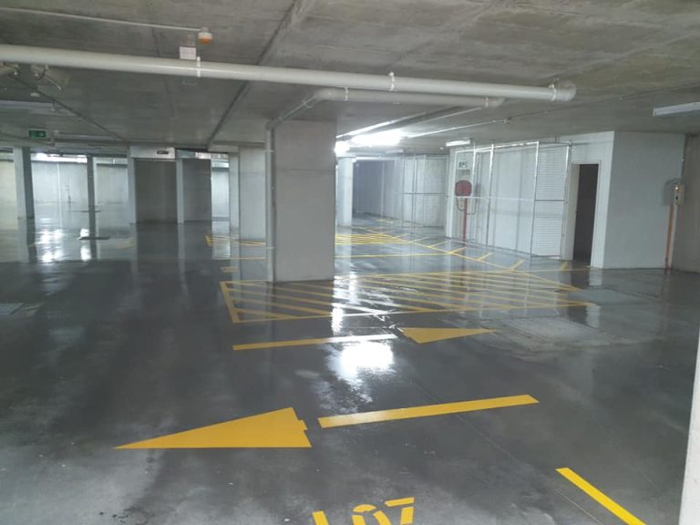 A parking garage featuring yellow arrows and markings on a freshly sealed concrete surface.