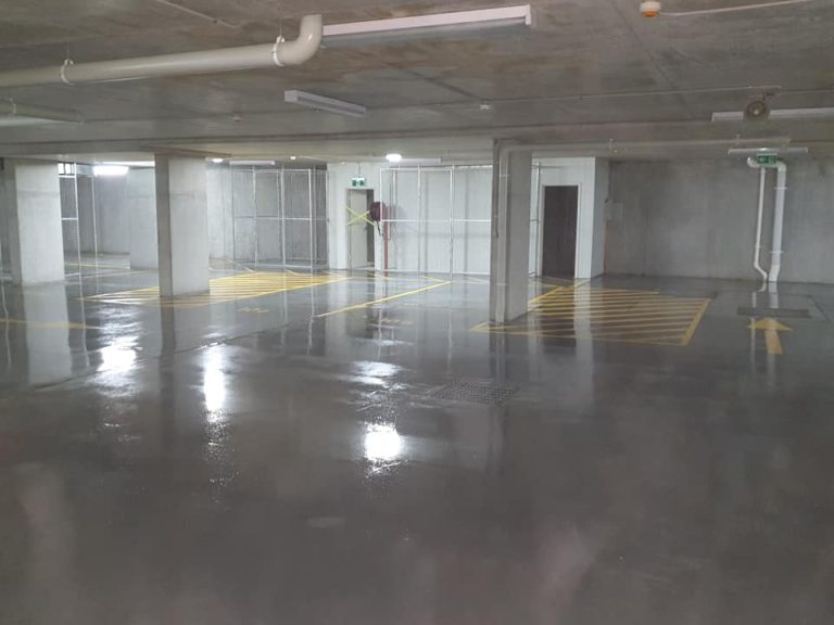 Interior view of a parking garage showcasing a vast concrete floor.