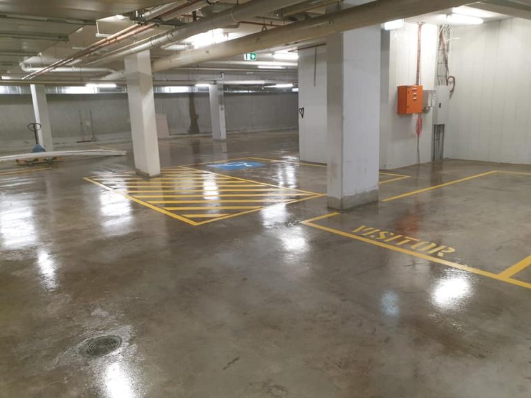 A parking garage characterized by yellow markings and a yellow sign.