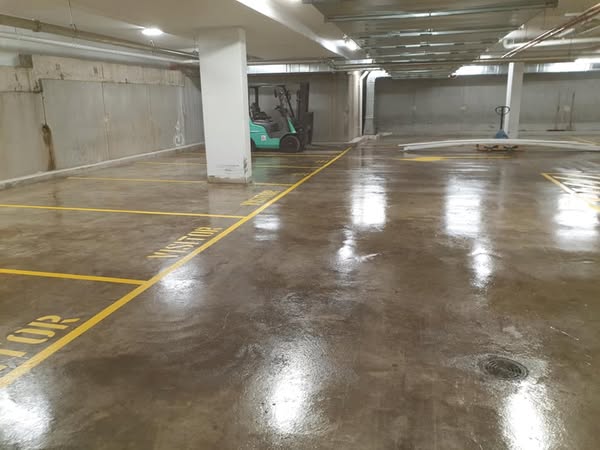 A parking garage featuring yellow lines on a sealed concrete floor.