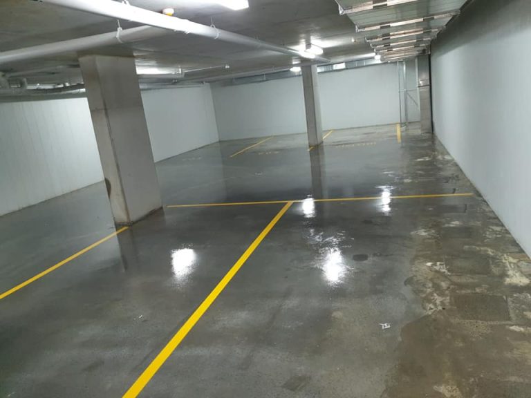 An expansive parking garage with yellow lines, showcasing a clean, sealed concrete surface.